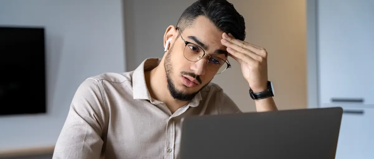 Man rubbing eyes in frustration at computer