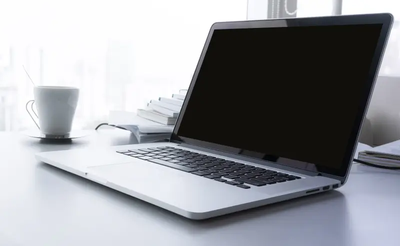 A MacBook with a blank screen sitting on a desk.